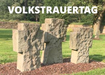 Ein Foto dreier steinerner Kreuze auf dem Friedhof in Donsbrüggen, darüber das Wort "Volkstrauertag"