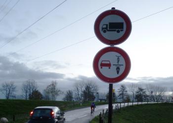 Das neue Verkehrszeichen an der Straße "Zum Breijpott" in Kleve. Außerdem ist ein Auto zu sehen, das hinter einem Fahrrad fährt.