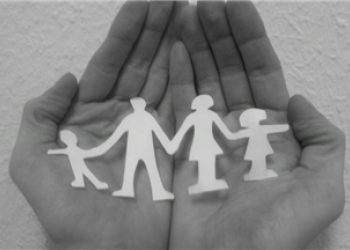 Zwei Hände halten ein Familie aus Papier